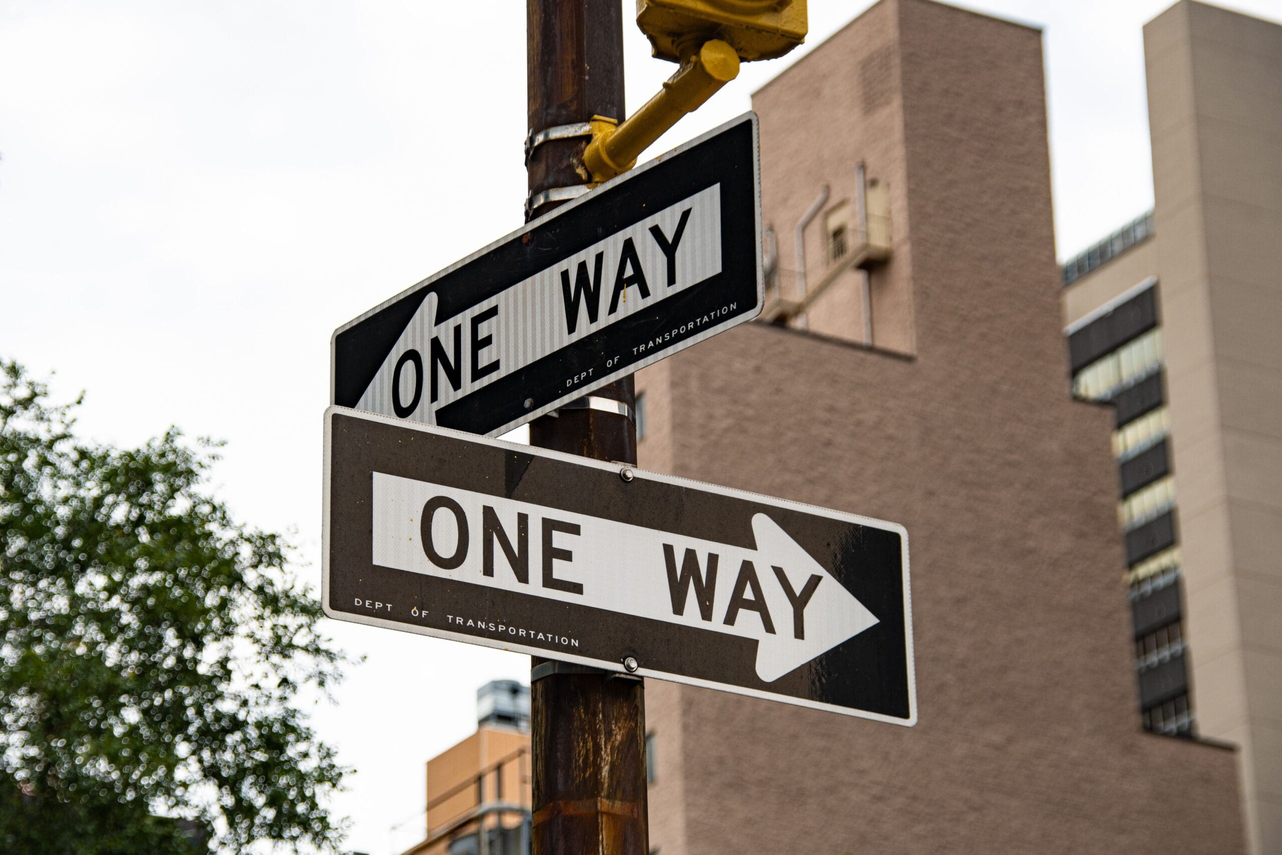 two road signs pointing different directions that say "one way"