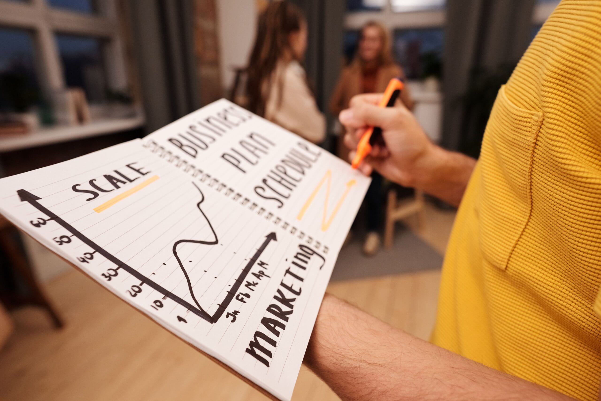 holding a notebook with a graph that says scale and marketing